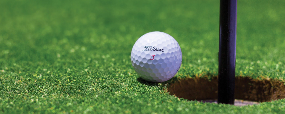 Golfball sitting on edge of hole